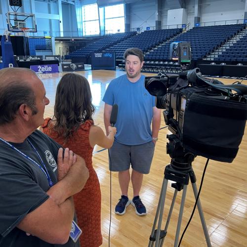 Charles Grant '03 tells WSYR TV Newschannel 9 reporter Isabella Colello and photographer Anthony Vecchio about his busy schedule. He'll be operating a live camera at both TBT in SRC Arena and the Baseball Hall of Fame Induction Ceremonies in Cooperstown.