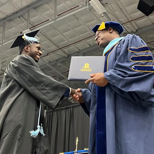 Juhudi Boazi (left) receives his degree from OCC President Dr. Warren Hilton (right).