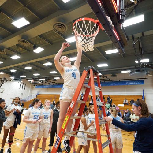 Student athlete cutting down the net after a game