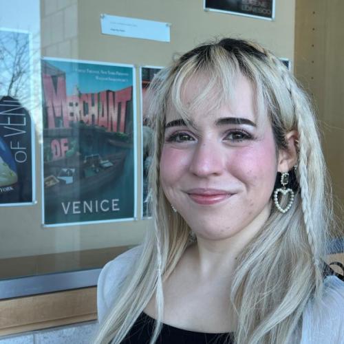 Abi Marin is a member of Student Government and a Graphic Design major. She's pictured in front of a "Merchant of Venice" poster she designed for class which is on-display in the Whitney Applied Technology Center.