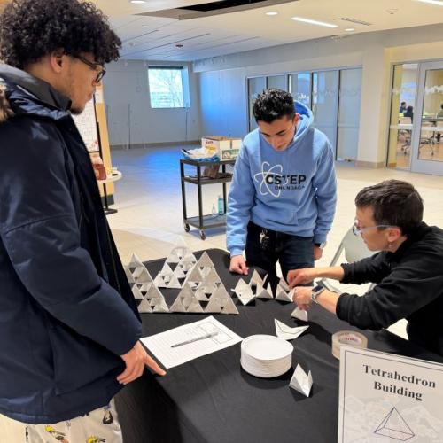OCC's Colleen Stevens (seated) helps students at the Tetrahedron Building station as Part of Louis Stokes Day. They are pictured in the lobby of Coulter Hall.