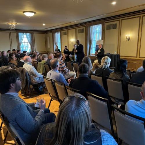 OCC President Warren Hilton (standing) speaks at the beginning of the Topics on Tap networking and panel discussion. Seated behind him (left to right) are Andrew Schuster, Lauren Staniec, Andy Breuer, and Glenn LaPoint '16.