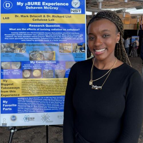 Dehaven McCray stands proudly in front of a poster board detailing her research as part of the USURE Science Symposium.