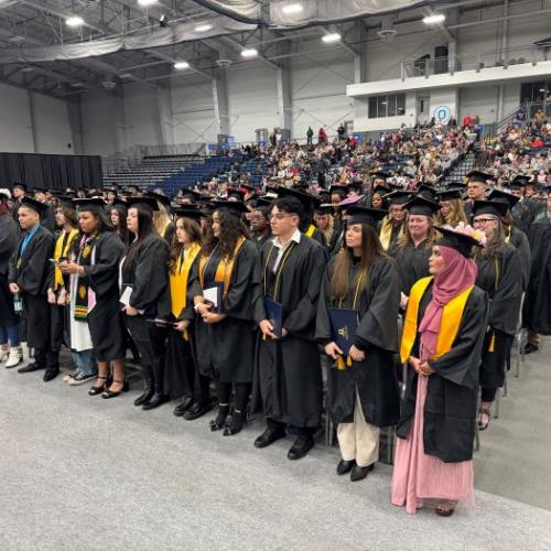 Onondaga Community College's newest alumni stand with their degrees before processing out of the SRC Arena.