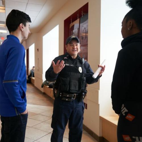 Onondaga Community College Peace Officer Rich Yung (center) speaks with students in the Gordon Student Center. Yung is the longest serving Peace Officer and the last original member of OCC's Campus Safety team.