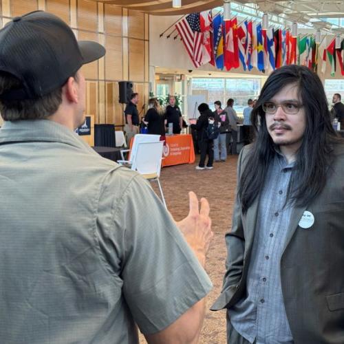 Onondaga Community College Welding major Ricky Stephens (right) speaks with a representative of Industrial Fabricating Corp at the STEM Career Showcase in the Gordon Student Center Great Room.