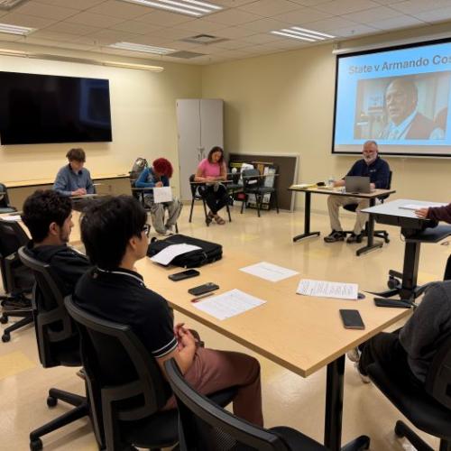 Student and prosecuting attorney Peyton George (standing, right) delivers her opening statements as part of the Criminal Investigations class final exam. Seated in front of the screen is Professor Pete Patnode who is acting as judge for the proceedings. 
