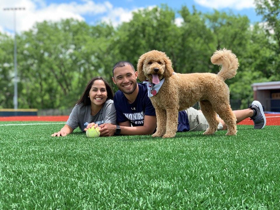 Justin and Jess laying on the OCC Softball Turf with their Dog