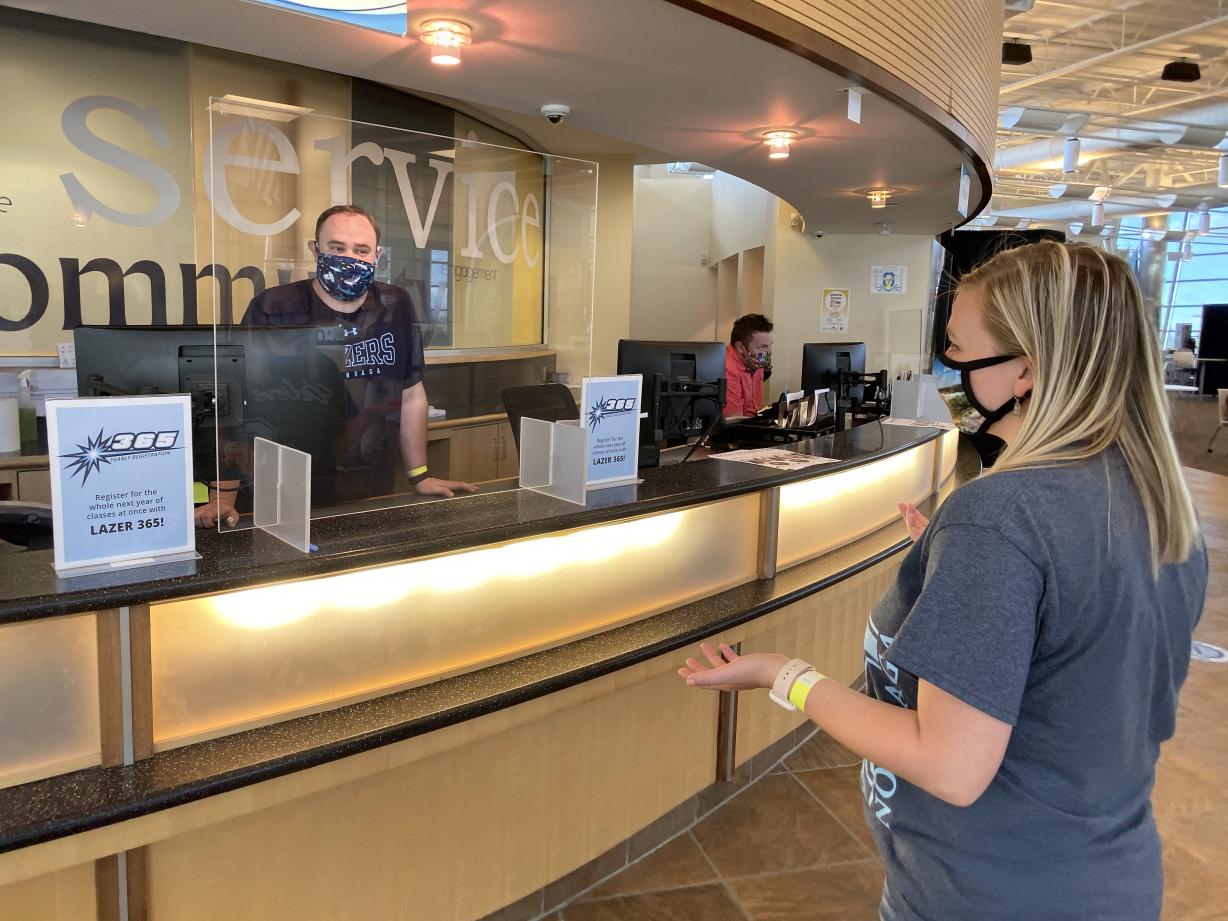 Student talking to an employee at the Student Central counter with masks and social distancing applied