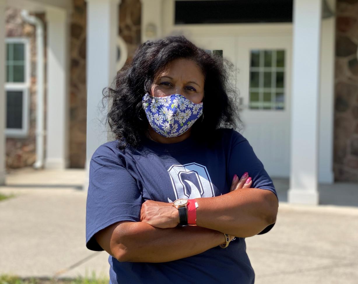 Woman standing in front of rest hall b wearing a mask with her arms folded