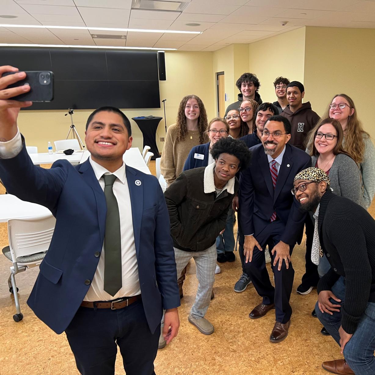 New SUNY Chancellor John B. King Jr. (in middle of group of students) poses for a photo with OCC students in Coulter Hall. Shooting the selfie is SUNY's Oscar Castillo.