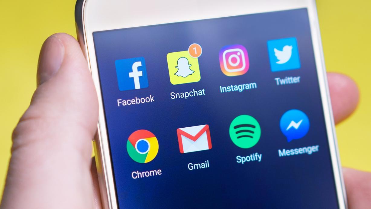 Person holding a smartphone with the social media icons displayed