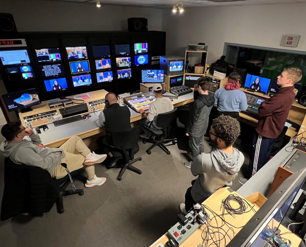 Professor Mark Ballard (wearing headset) leads students through a television production in the Broadcast Media Communication studios in the Whitney Applied Technology Center. Professor Mark Ballard (wearing headset) leads students through a television production in the Broadcast Media Communication studios in the Whitney Applied Technology Center.