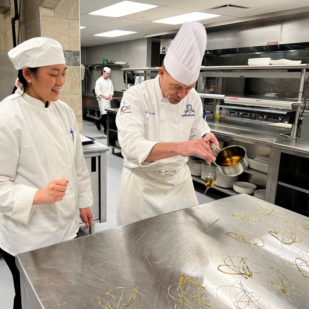 Chef James Taylor (right) shows student Kiersten Coates (left) the proper technique for making "sugar ornaments" which will be placed on top of desserts. They are working in the kitchen which is attached to Stonewalls restaurant in the Gordon Student Center. Chef James Taylor (right) shows student Kiersten Coates (left) the proper technique for making "sugar ornaments" which will be placed on top of desserts. They are working in the kitchen which is attached to Stonewalls restaurant in the Gordon Student Center.