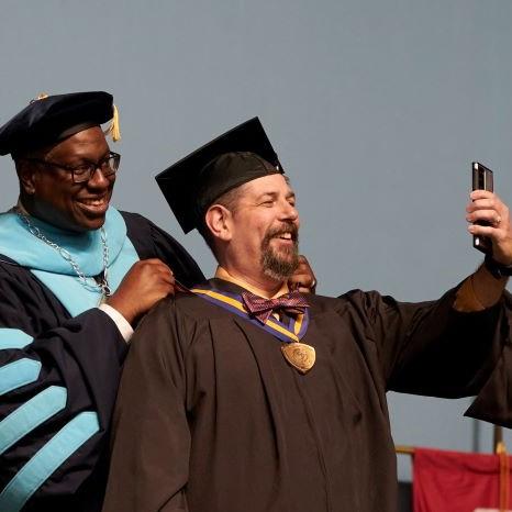 Keith Edwards (right) shoots a selfie with OCC President Dr. Warren Hilton (left) after being awarded his SUNY Chancellor's Award for Excellence during commencement. Keith Edwards (right) shoots a selfie with OCC President Dr. Warren Hilton (left) after being awarded his SUNY Chancellor's Award for Excellence during commencement.