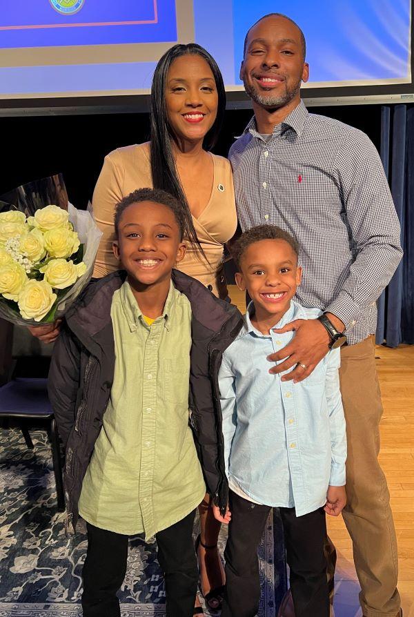 Jamira Williams '23 proudly wears her Nursing pin while pictured with her husband Quindell '08, and sons Jasai (green shirt), and Qaiel (blue shirt).