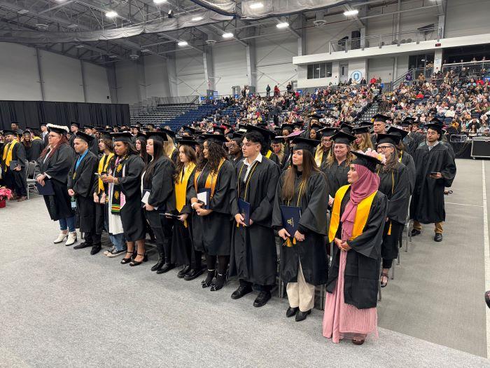 Onondaga Community College's newest alumni stand with their degrees in the SRC Arena.