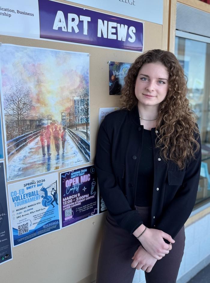 Grace Plewak is pictured next to her watercolor painting which was used with OCC's holidays cards and messaging.