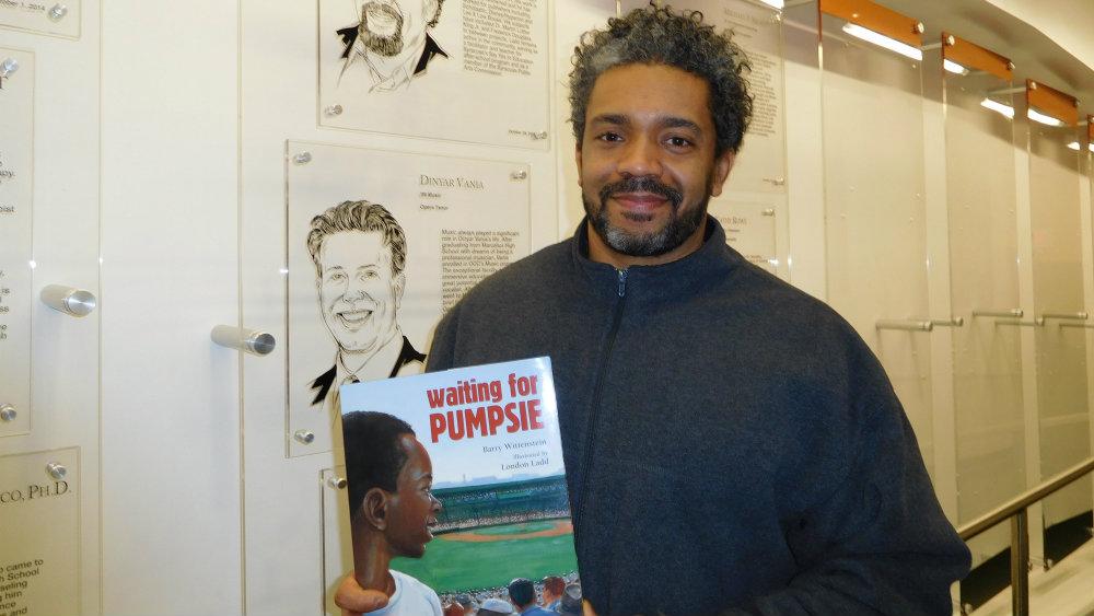 Ladd in front of is Alumni Face Plaque in Academic II Building.