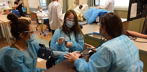 Nursing Students with full medical gear performing a procedure
