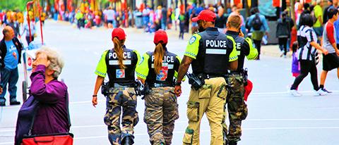 Police officers walking with their back turned showing their POLICE vest in a crowd